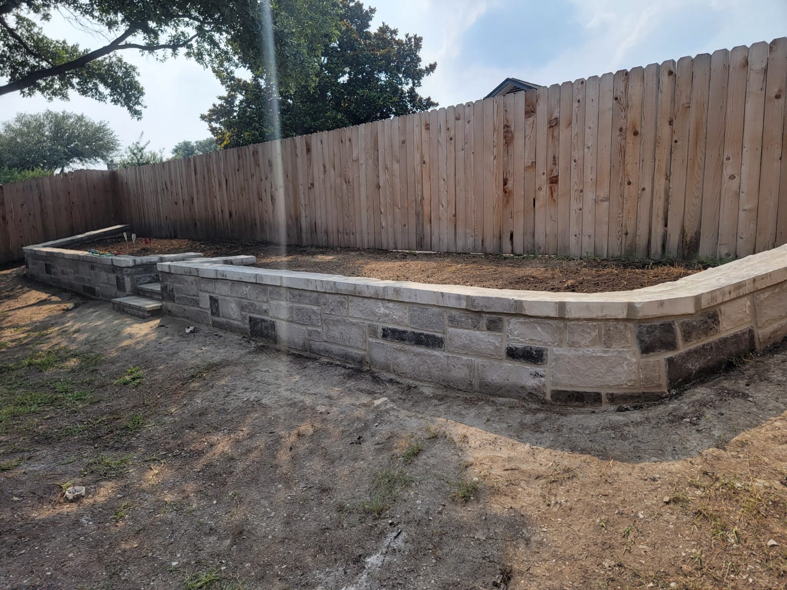 Finished retaining wall with stone cap and integrated landscape bed